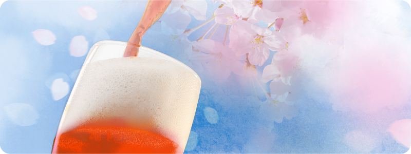 グラスにビールを注いでいる写真、背景に桜吹雪
